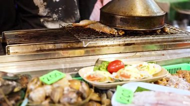 Kalabalık bir gece pazarında taze deniz ürünleri sergileniyor.