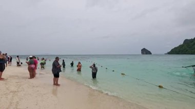 İnsanlar Krabi sahilinde yürüyor ve yüzüyor.