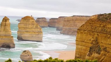 Avustralya, Port Campbell 'da bulutlu gökyüzü altında kireçtaşı yığınlarına çarpan 12 havarinin huzurlu manzarası.