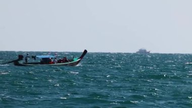 Uzun kuyruklu bir tekne Phuket, Tayland yakınlarındaki canlı mavi denizi aşarak kıyı macerasının özünü yakalıyor.
