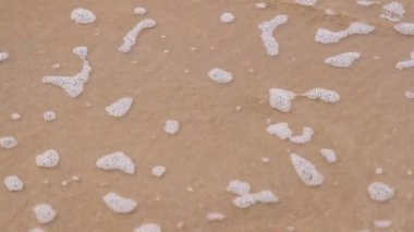 Okyanus dalgaları yavaşça kumlu sahilden çekiliyor