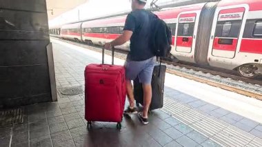 Bagajlı adam yüksek hızlı tren peronuna yaklaşıyor.