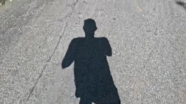 Bir insanın gölgesi kaldırımda yürür..