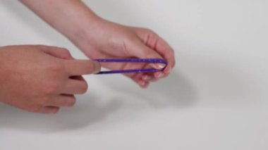 Elleri parlak mor bir saç teli çekiyor.