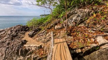 Parlak gün ışığında ahşap köprüleri ve kayalık arazisi olan sakin bir sahil yolu büyüleyici okyanus manzarası sunuyor.