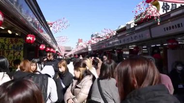 Yayaların ve dükkanların bulunduğu kalabalık bir alışveriş merkezi.