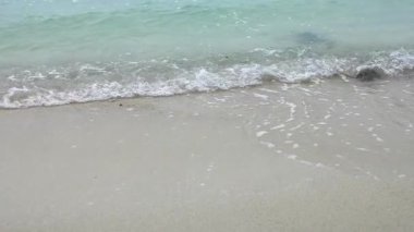 Dalgalar yavaşça kumlu kıyıya vurur