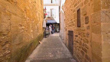 İnsanlar dar, tarihi bir sokakta yürüyorlar.