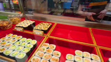 Melbourne 'daki bir lokantada canlı bir suşi gösterisi çeşitli rulo ve tabaklar parlak ışıklandırma altında, mutfak sanatını ön plana çıkarıyor.