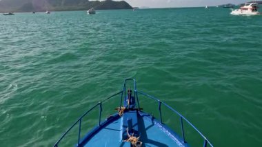 Canlı bir mavi tekne, Phuket 'in zümrüt sularında, berrak gökyüzünün altında, sakin bir deniz macerası yakalıyor.