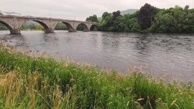 Sakin nehir tarihi taş köprünün altından akıyor.