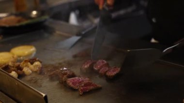Şef bifteği ve ızgarayı ustalıkla hazırlar.