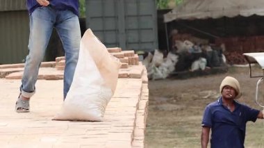 İki işçi koordineli bir çabayla bir çantayı fırlatıyor.