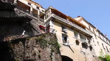 Balkonu ve yeşilliği olan bir uçurum kenarı binası.