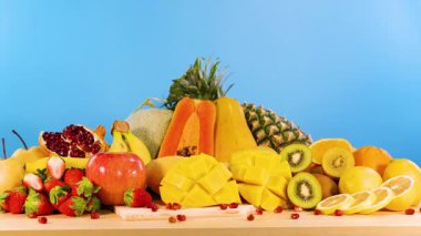 Mavi bir zemin üzerinde canlı meyveler sergilenir