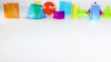 Bir el, eğitici ve oyuncu unsurları vurgulayarak, beyaz arka planda canlı üç boyutlu geometrik şekillerle etkileşir