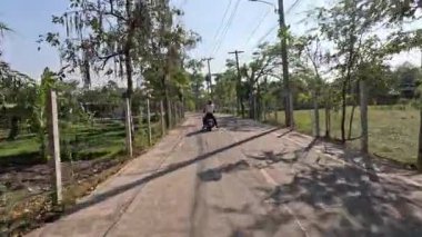 Huzurlu bir kırsalda motosikletli geziyor.