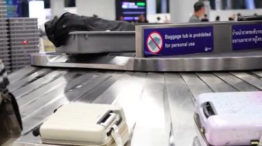 Bavullar bagaj teslim atlıkarıncasında taşınıyor.