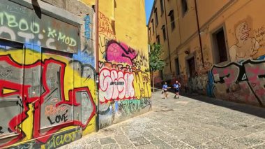 Sokakta yürüyen insanların olduğu renkli grafitiler.