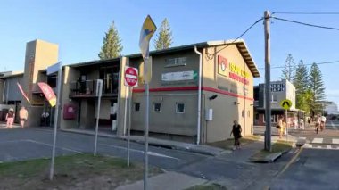 Güneşli bir sahil kasabasında yayalar ve araçlar