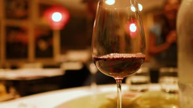 Altın Sahil mekanında sıcak ve çevresel bir arka planı olan bir şarap kadehi. Yumuşak ışıklandırma samimi atmosferi güçlendirir