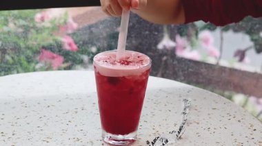 Kırmızı bir içkiyi pipetle karıştırıyorum.