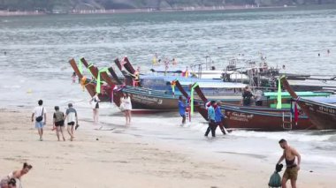 İnsanlar Krabi sahilinde teknelerle yürüyor.