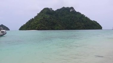 Tekne sahile yaklaşıyor, insanlar kıyıda toplanıyor.