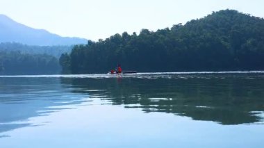 İki kanocu sakin bir gölde huzur içinde kürek çekiyor.