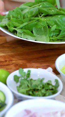 Bir insan iyi aydınlatılmış bir mutfak ortamında taze fesleğen yaprakları hazırlar.