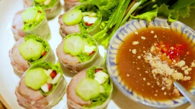 Vietnam usulü, taze sebzeli ve soslu domuz dürümleri. Parlak ışıklandırma canlı renkleri ve dokuları vurgular