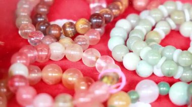 Kırmızı kumaşta renkli değerli bilezikler.