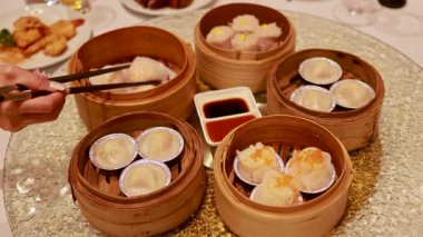 Eller yemek çubuklarını bambu buharlı buharlı tencerelerden halka açık bir yemek deneyimi yaratmak için kullanır.