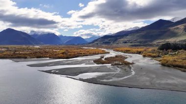 Hava görüntüleri Glenorchy 'nin dağlık arazisinde parçalı bulutlu bir gökyüzünün altında kıvrılan sakin bir nehri yakalıyor.