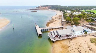İnsansız hava aracı görüntülerinde Barwon Heads 'in manzaralı kıyı şeridi ve iskelesi yumuşak gün ışığında sakin suları ve kumlu sahilleri gösteriyor.