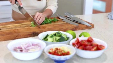 Closeup view of woman chopping herbs at the kitchen