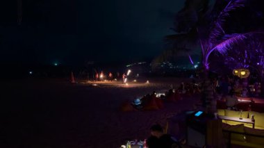 Phuket 'te loş bir plajda büyüleyici bir ateş dansı, canlı ışıklandırma ve dinamik hareketlerle