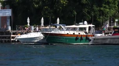 people walking on pier with boats on lake 
