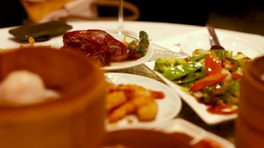 Çin restoranında sıcak ışıkta yakalanan karides ve sebzeler de dahil olmak üzere canlı bir Dim Sum yemeği dizisi.