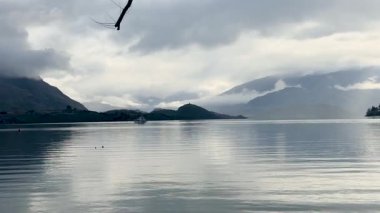 Wanaka Gölü 'nün sakin manzarası. Dağlar ve bulutlar. Yumuşak, dağınık ışık altında yakalanmış.