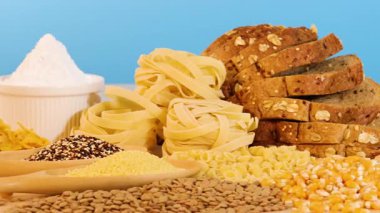 Parlak mavi arkaplanı olan bir masada çeşitli tahıl ve ekmekler gösterilir, dokular ve renkler vurgulanır