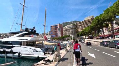 Cyclist rides along marina with yachts docked