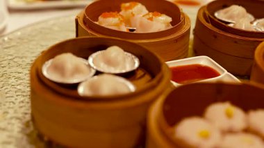 A variety of dim sum dishes in bamboo steamers on a table. Warm lighting enhances the inviting dining atmosphere