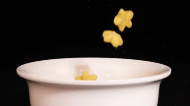 Star-shaped cereal pieces drop into a white bowl against a black background, creating a dynamic and visually appealing scene