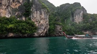 Tekne, yüksek kireçtaşı kayalıklarının yakınından geçiyor.