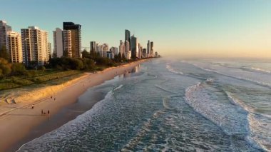 Aerial view of Gold Coast's beach and skyline at sunrise, capturing waves and serene morning light