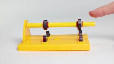 A sequence showing magnets on a yellow stand rotating due to magnetic forces, illustrating attraction and repulsion
