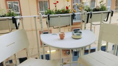 Kahve ve kül tablasıyla sessiz bir balkon sahnesi