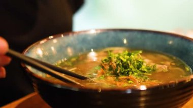 Çubuklar, taze otlar ve zengin et suyunun altını çizen, buharı tüten bir Vietnamlı kabından taze sığır eti kaldırır.