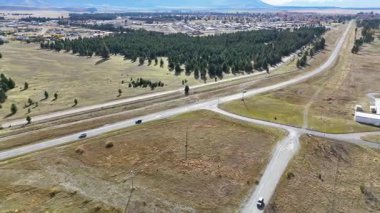 İnsansız hava aracı görüntüleri, temiz gökyüzünün altında ağaçlarla ve açık arazilerle kırsal bir arazide manzaralı bir yol yakalıyor.